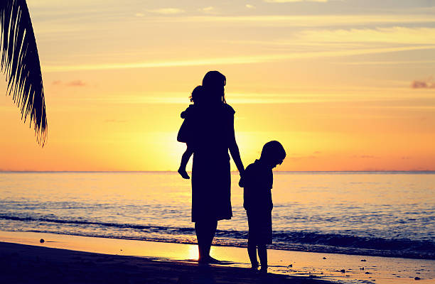 istock mother and two kids walking on beach at sunset 496235150