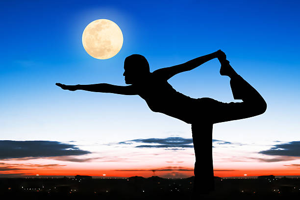 istock Silhouette young woman practicing yoga  on night full moon backg 496235160