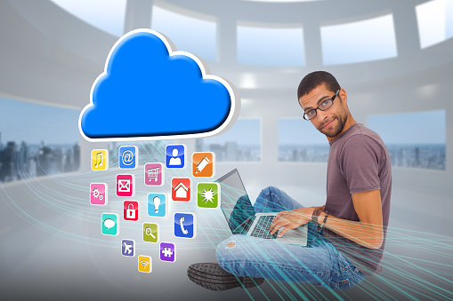 Digital composite of casual man using laptop with app icons and cloud
