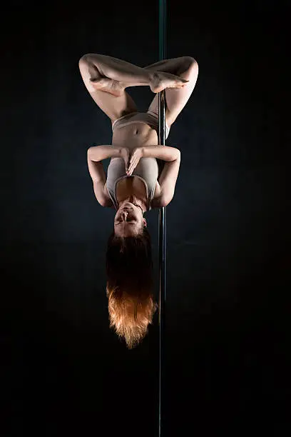 Young woman in meditation Lotus position upside down on pole