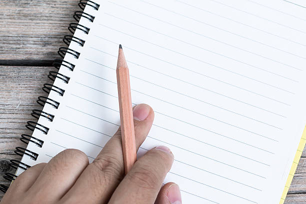 istock Hand Hold Pencil with Notebook on wood background 496237236