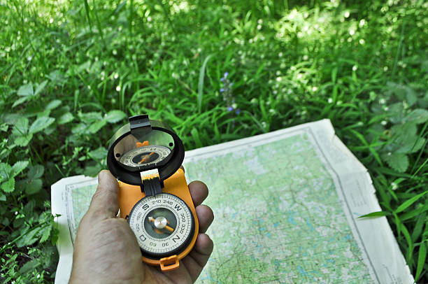 compass in der hand gegen hintergrund der karte. - boy scout orienteering compass map stock-fotos und bilder