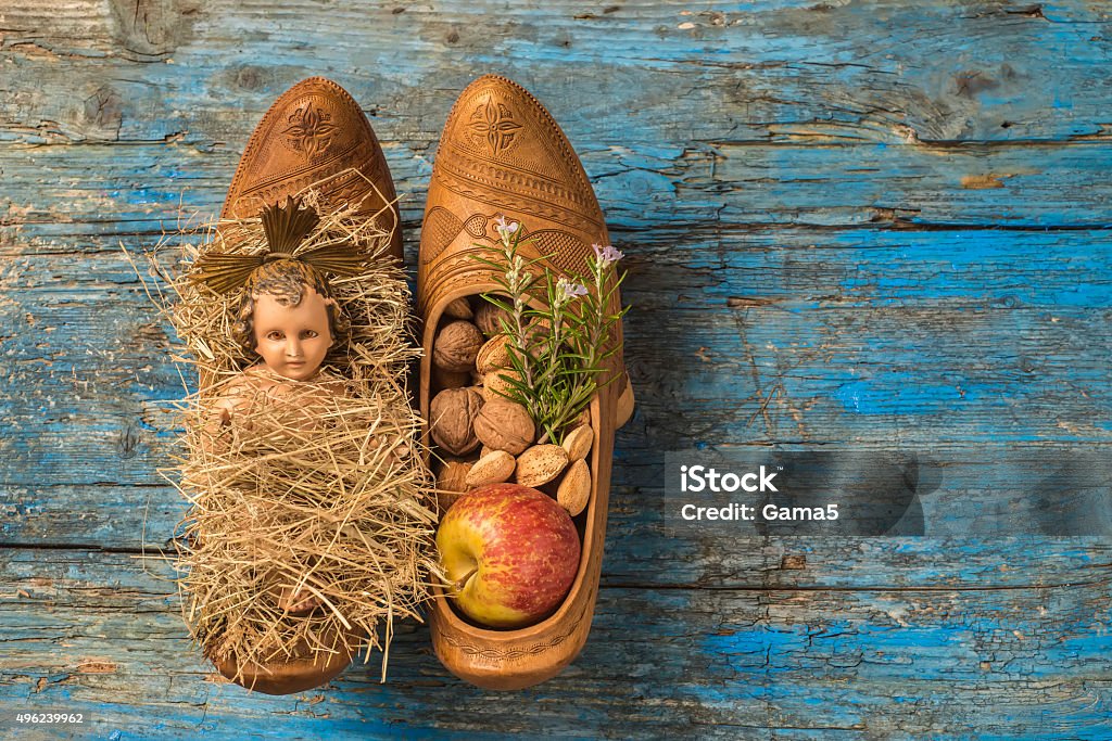 Christmas background Baby Jesus Christmas time,ancient figurine of Baby Jesus and offerings in traditional farmer clogs, on rustic background Nativity Scene Stock Photo