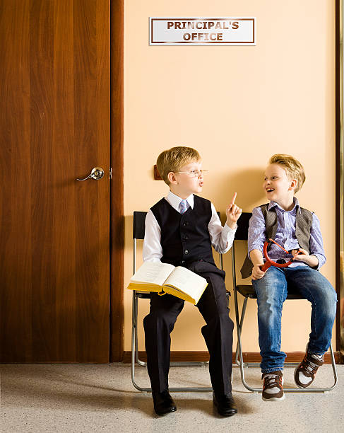 Two little twins. Two identical babies in white clothes for children sit on a sofa in the warmth of home and hold a biscuit in their hand. Spontaneous portrait of twins with blue eyes and blonde hair
