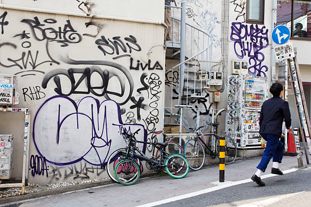 Berlin, Germany – December 14, 2025: Abandoned bicycle lying on the ground near graffiti covered residential buildings and urban greenery.
