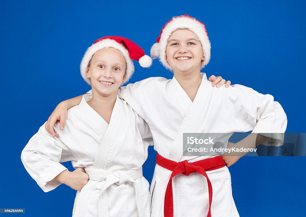 Children in caps of Santa Claus are standing with smile Children in karategi and caps of Santa Claus are standing with a smile 2015 Stock Photo