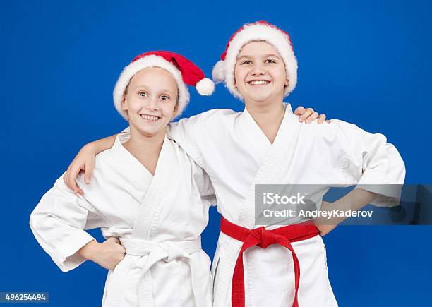 Children In Caps Of Santa Claus Are Standing With Smile Stock Photo - Download Image Now