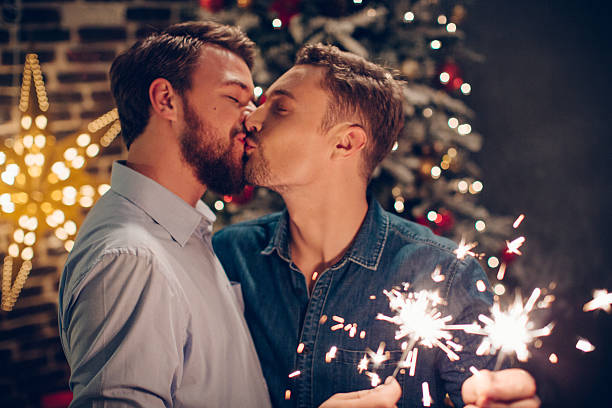 pareja la celebración de navidad juntos. - gay man homosexual men kissing fotografías e imágenes de stock