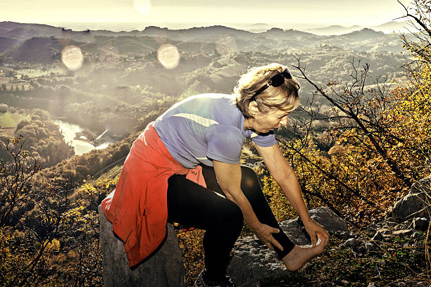 Mature  woman sitting,runner looks injured leg,Brda,Slovenia,Europe Mature  woman sitting, runner looks injured leg, smoke bush,lens flare, Sabotin,Brda, Nova Gorica,Primorska, Slovenia, Europe.  Autumnal coloures.Nikon D3x primorska white sport nature stock pictures, royalty-free photos & images