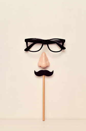 eyeglasses, nose and mustache, depicting a man face, on a beige background
