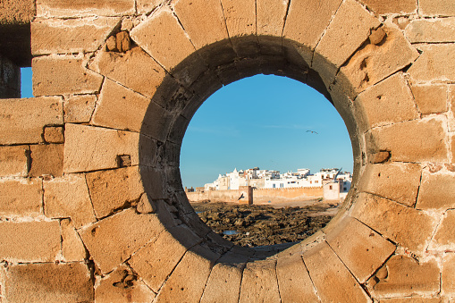 View through a circle hole in the fortification on the coast and city Essaouira, Morocco.