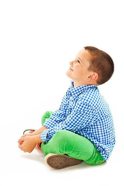 Child playing in chair, dressed in blue and white background, long curly hair, smiling.