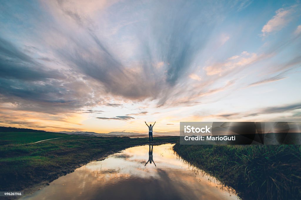 Young man at sunset A young man reflected on a puddle at sunset Hope - Concept Stock Photo