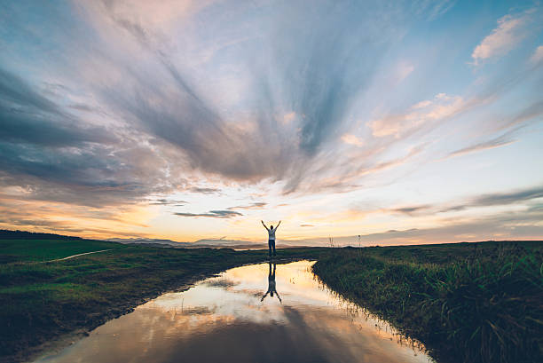 jovem homem no pôr do sol - arms outstretched fotos - fotografias e filmes do acervo