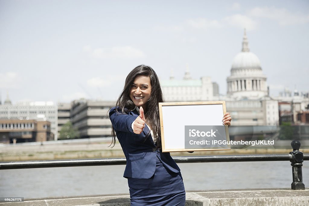 Beautiful Indian businesswoman Indian businesswoman gesturing thumbs up as she holds Moodboard sign with St. Paul's Cathedral in background 20-29 Years Stock Photo