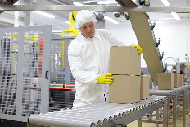 istock worker in white apron at packing line in factory 496262429
