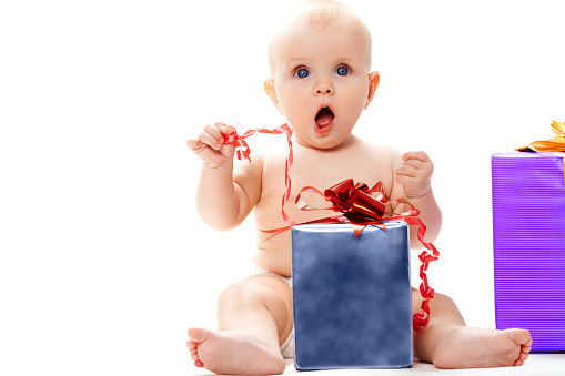 Photo of surprised baby sitting with big giftbox by her side over white background    Note to inspector: the image is pre-Sept 1 2009