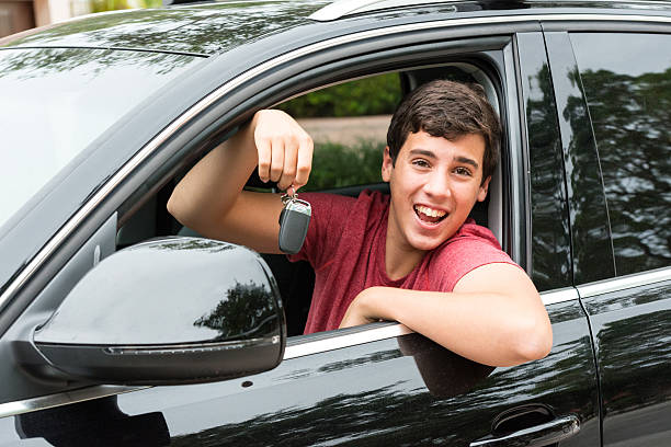 Got his first vehicle Teenage boy sitting inside his brand new Import SUV vehicle proudly showing his car keys teenager boy driving stock pictures, royalty-free photos & images