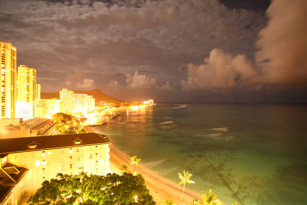 vista nocturna de la playa de waikiki - hawaii islands big island waikiki beach fotografías e imágenes de stock