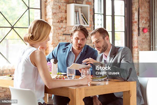 Business Colleagues Using A Digital Tablet During Lunch Stock Photo - Download Image Now