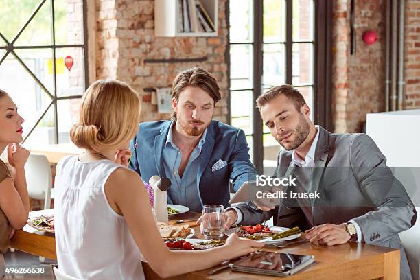Business Colleagues Using A Digital Tablet During Lunch Stock Photo - Download Image Now