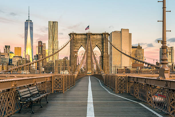 Brooklyn Bridge and Lower Manhattan at Sunrise, New York City The Famous Brooklyn Bridge at Sunrise, New York City, USA. The sun is rising over Brooklyn on this beautiful day of Autumn international landmark stock pictures, royalty-free photos & images