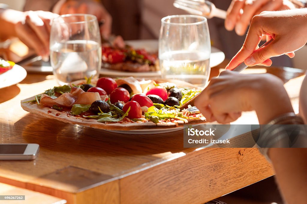 Woman eating pizza in the restaurant Woman eating pizza in the restaurant. Close up of hands and pizza. Unrecognizable person. 2015 Stock Photo