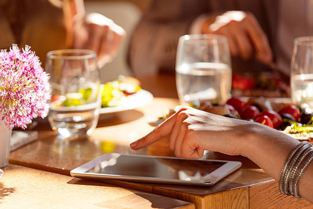 женщина с помощью цифрового планшета в ресторане - close up touchpad computer index finger стоковые фото и изображения