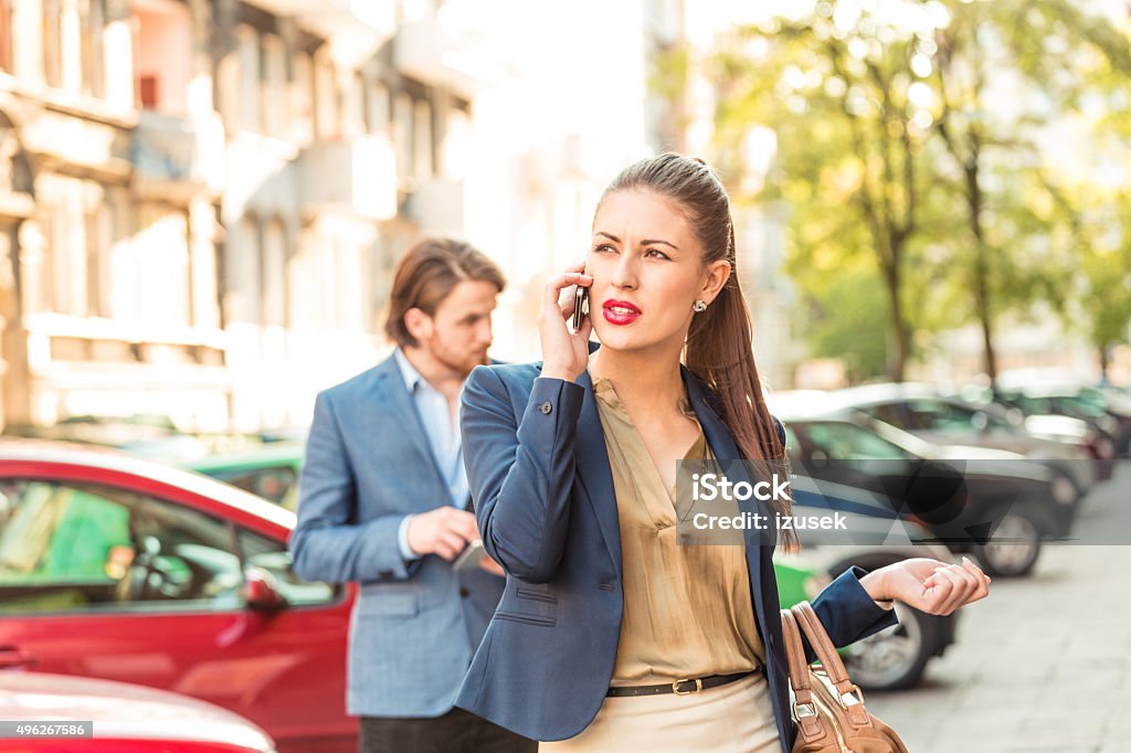 Young businesswoman talking on phone outdoors Portrait of young businesswoman standing on the street in the european city, talking on smart phone.  2015 Stock Photo