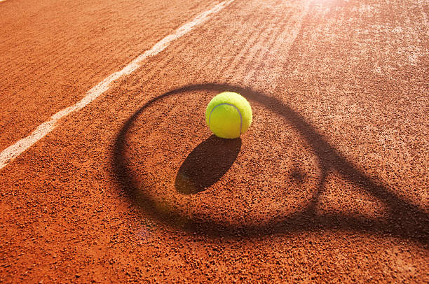 tennis-ball und schläger schatten auf sandplatz - tennis stock-fotos und bilder