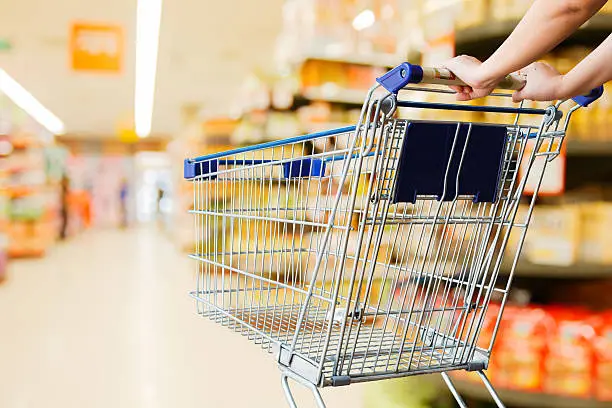 Photo of woman pushing shopping cart in supermarket