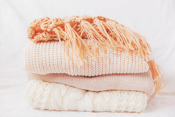 istock Pile of beige woolen clothes on a white background. 496287358
