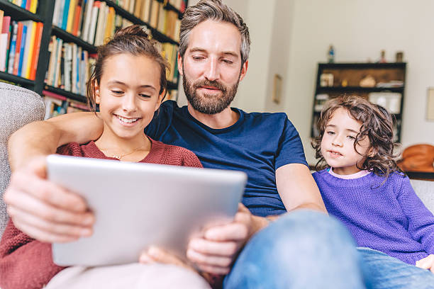 istock Happy father with two girls using digital tablet 496287942