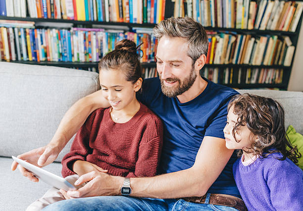 istock Happy father with two girls using digital tablet 496288180