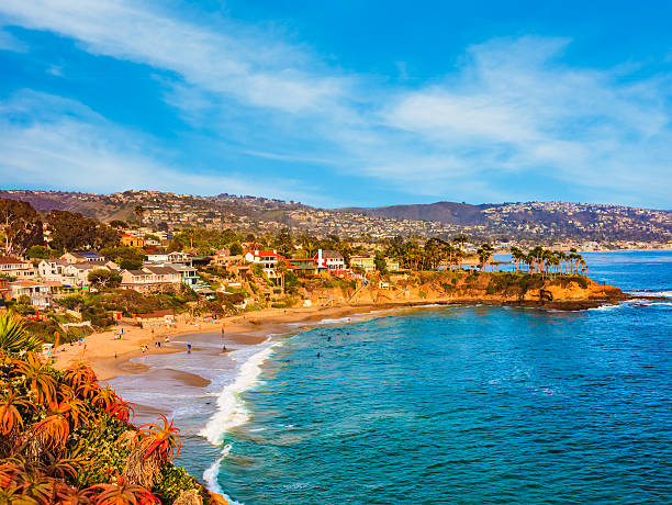 Laguna Beach coastline,Pacific Ocean,Rte 1,Orange County,CA Rocky cliffs with palm trees fill the leftside foreground leading back to beach and breaking surf of Laguna Beach and city with hillside houses, California laguna beach california photos stock pictures, royalty-free photos & images