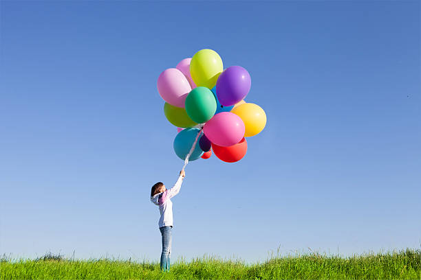 istock Happy woman jumping with balloons 496307355