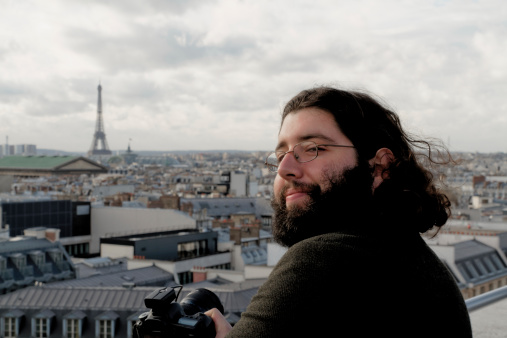 Tourist who prepares his camera to photograph roofs and Parisian monuments