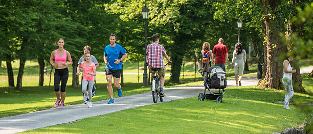 People jogging in park Family jogging and man cycling in park, people walking in background. carriage photos stock pictures, royalty-free photos & images