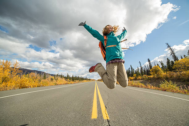 istock Cheerful traveler jumping high up on road 496309170