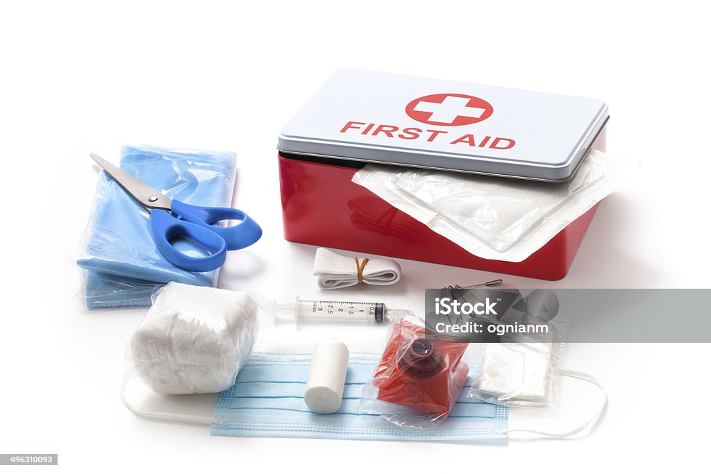 First Aid Kit Box and it Content Box of first aid kit isolated on white background. Out of the box is it content: bandage, syringe, gauze, scissors, cotton, mask and other accessories needed in cases of accidents. The first aid kit equipment in the vehicles is required by law all over the world. First Aid Kit Stock Photo