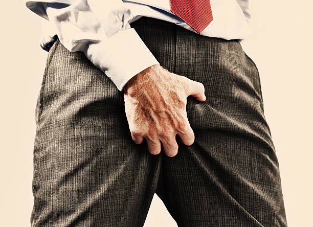 Businessman scratching groin through clothes Cropped view of businessman in formal clothes grabbing his genitals through his clothes, maybe he's itchy but it's very vulgar behavior and sexist too! testis stock pictures, royalty-free photos & images