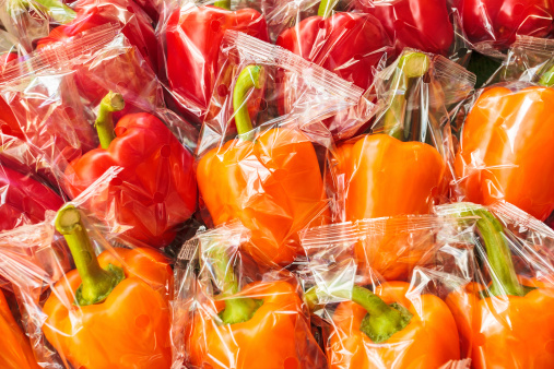 Bunch of plastic wrapped orange and red bell peppers