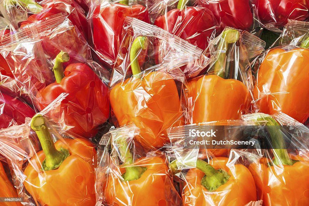 Bunch of plastic wrapped bell peppers Bunch of plastic wrapped orange and red bell peppers Plastic Stock Photo