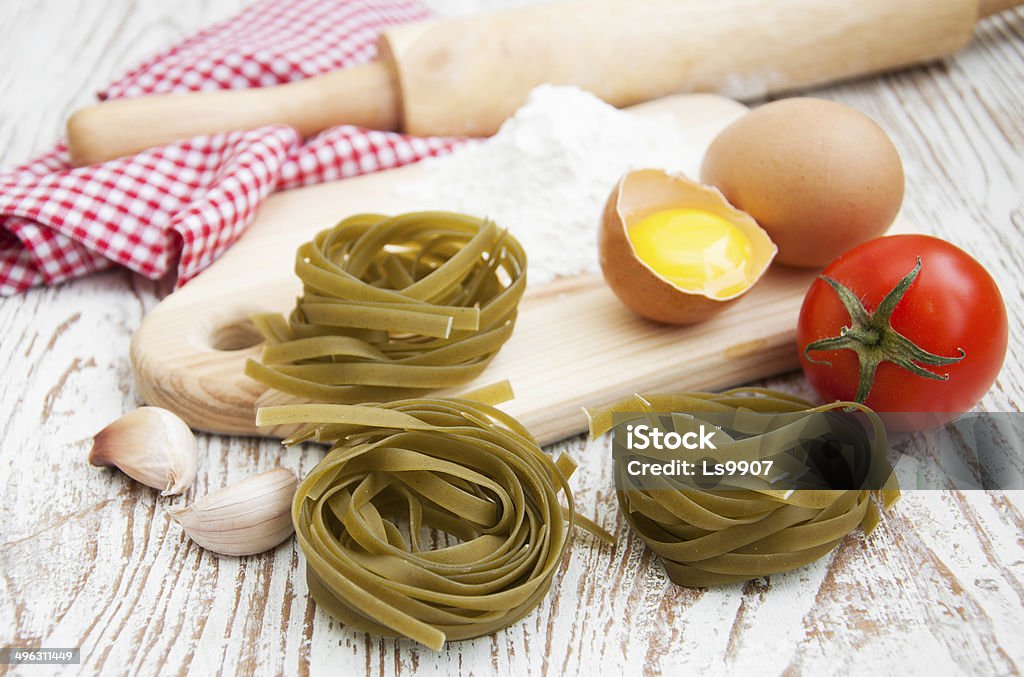 Raw homemade pasta Fresh homemade tagliatelle, eggs and rolling pin on a table Basil Stock Photo