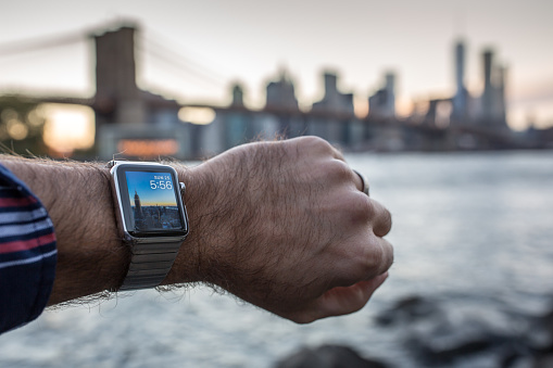 New York, United States- October 25, 2015: Man wearing and using a 42mm 316L Stainless Steel Apple Watch in New York City while looking at the sunset. The Apple Watch became available April 24, 2015 and is the latest device produced by Apple.