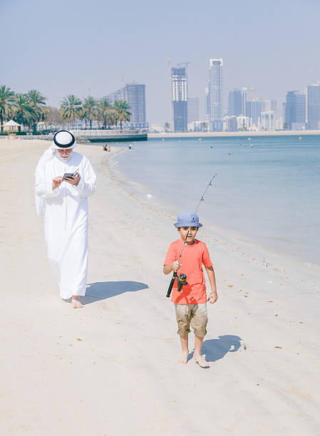 istock Arab grandfather and little boy having fun at beach 496320432