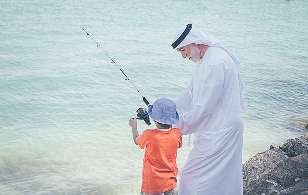 istock Arab grandfather and little boy having fun at beach 496320584
