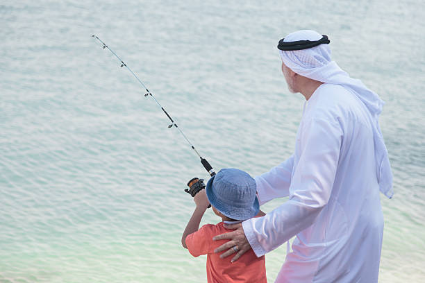 istock Arab grandfather and little boy having fun at beach 496320672