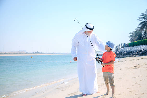 istock Arab grandfather and little boy having fun at beach 496320908
