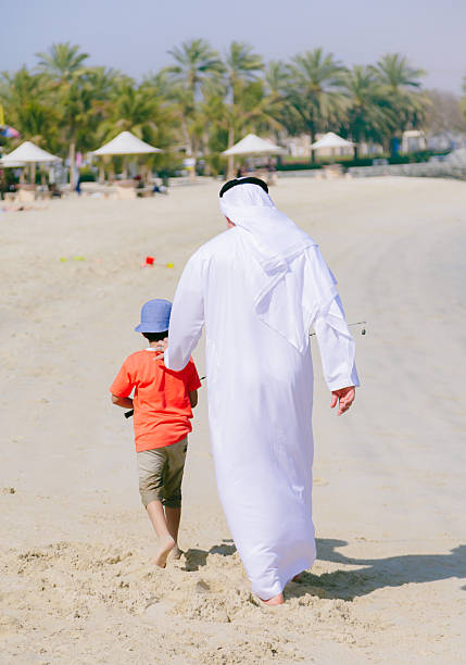 istock Arab grandfather and little boy having fun at beach 496321172